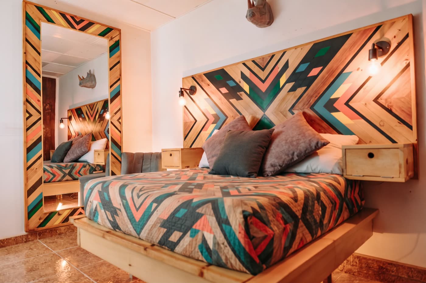 Room Tribal con cabecero geométrico multicolor y espejo de madera