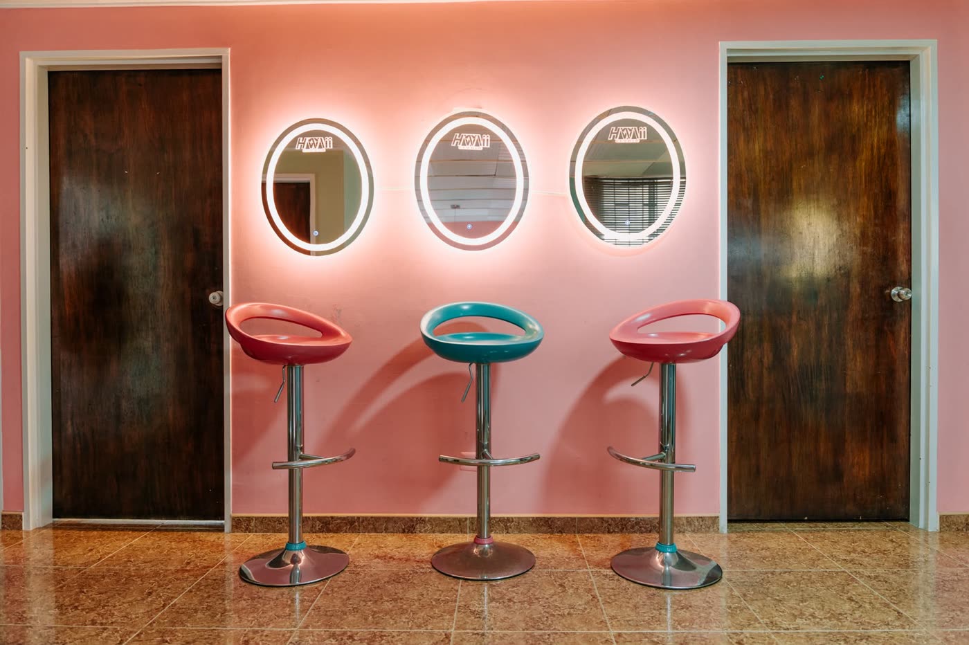 Camerino rosado con tres espejos redondos iluminados con el logo Hawaii